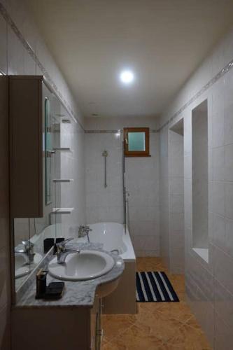 La salle de bains blanche est pourvue d'un lavabo et d'une baignoire. dans l'établissement Maison du Buis doré, à Pollieu