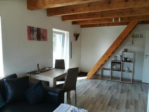 a living room with a wooden table and a desk at Sonnige Zimmer in Eberhardzell