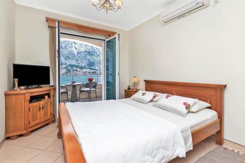 a bedroom with a bed and a tv and a window at Apartments Jovanovic in Kotor