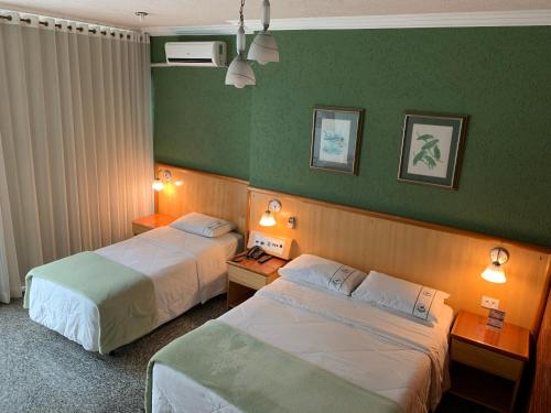 2 camas en una habitación de hotel con paredes verdes en Residencial Pantanal Chácara Klabin, en São Paulo