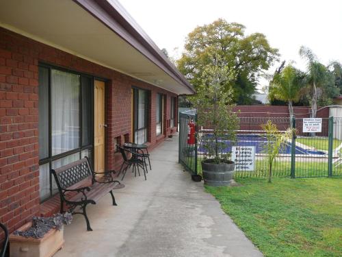 un edificio con bancos en una acera junto a una valla en Murray River Motel, en Swan Hill