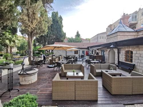 an outdoor patio with couches and tables and chairs at Sergei Palace Hotel in Jerusalem
