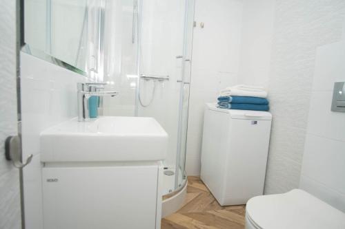 een witte badkamer met een wastafel en een toilet bij Apartament Skwer 13 in Gdynia