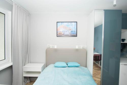 een slaapkamer met een bed met twee blauwe kussens bij Apartament Skwer 13 in Gdynia