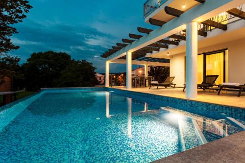 a villa with a swimming pool at night at Luxury Villa Rivabel in Malinska