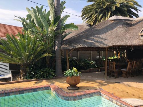 a house with a pool with a thatch roof at Annies Place Self Catering in Kempton Park