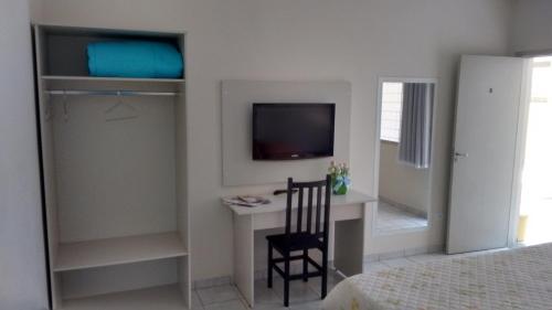 a bedroom with a desk with a television and a chair at Hotel Picadão in São Pedro