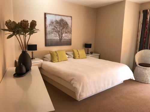 a bedroom with a large white bed with yellow pillows at Sunset Apartment in Cape Town