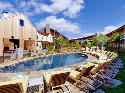 a row of lounge chairs next to a swimming pool at Lone Star Court, by Valencia Hotel Collection in Austin
