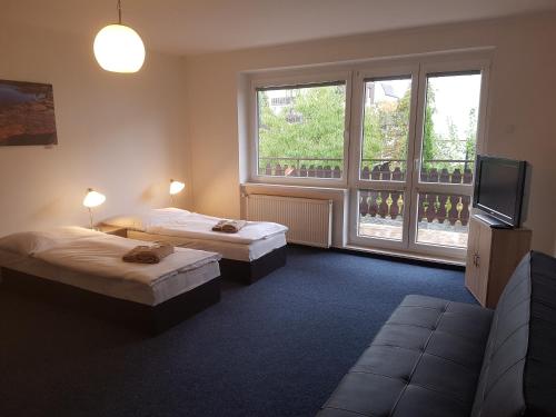 Habitación con 2 camas, TV y ventanas. en Apartmany Chodov, en Praga