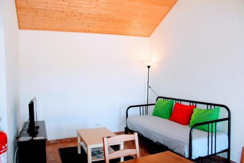 a room with a bed with green and red pillows at Monte Costa LuZ in Porto Covo