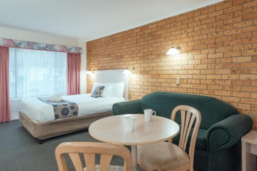a hotel room with a bed and a couch and a table at Coffs Windmill Motel in Coffs Harbour