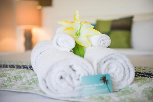 a pile of towels and a flower on a bed at Baybliss Apartments 1 Bedroom WiFi in Shute Harbour