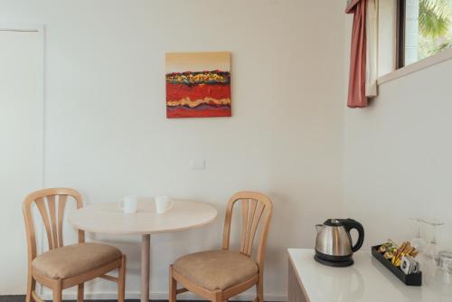 a kitchen with a table and two chairs at Coffs Windmill Motel in Coffs Harbour