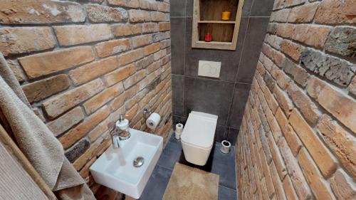 a bathroom with a white sink and a brick wall at Apartmán Sofia s infrasaunou, PRIMO, Starý Smokovec in Smokovce