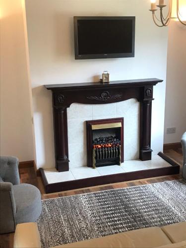 a living room with a fireplace with a tv above it at Hebridean Holiday House in Stornoway
