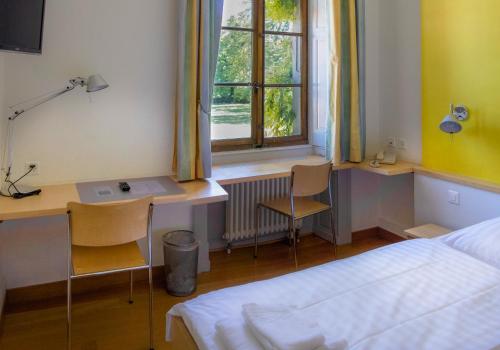 a bedroom with a bed and a desk and a window at Château de Bossey in Bogis-Bossey