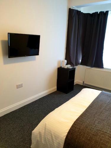 ロンドンにあるWanstead Hotelのベッドルーム1室(ベッド1台、壁掛け薄型テレビ付)