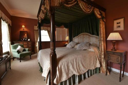 a bedroom with a canopy bed and a chair at Kilmokea Country Manor & Gardens in New Ross