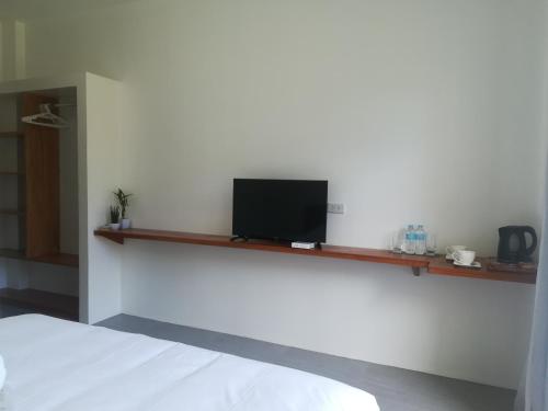 ein Schlafzimmer mit einem Bett und einem TV auf einem Regal in der Unterkunft Christelle Inn in Panglao