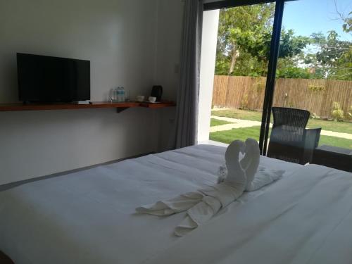 a bedroom with a bed with white sheets and a television at Christelle Inn in Panglao