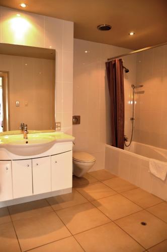 a bathroom with a sink and a tub and a toilet at St James Apartments in Queenstown
