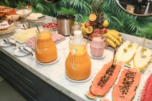 a buffet with fruit and juice and sandwiches and drinks at Hotel da Praça in Bonito