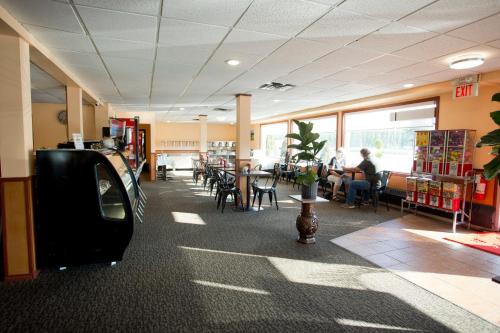 uma cafetaria com mesas e cadeiras e pessoas sentadas a mesas em Valemount Vacation Inn em Valemount