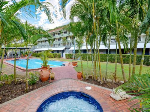 a swimming pool in front of a resort with palm trees at Hibiscus Apartments on Hamilton Island by HIHA in Hamilton Island