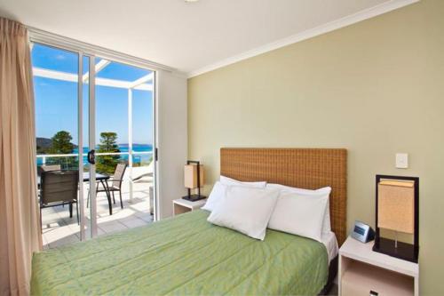 a bedroom with a bed with a view of the ocean at Ettalong Beach Luxury Apartments in Ettalong Beach
