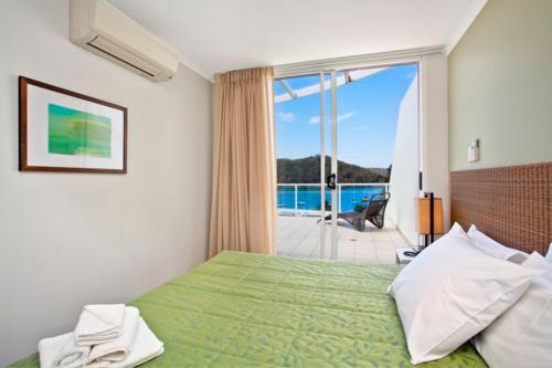 a bedroom with a green bed with a view of the ocean at Ettalong Beach Luxury Apartments in Ettalong Beach