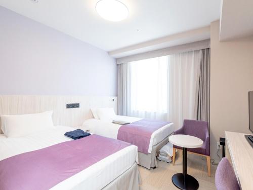 a hotel room with two beds and a chair at Hiyori Hotel Osaka Namba Station in Osaka