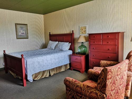 a bedroom with a bed and a chair at Hotellerie Jardins de Ville in Sherbrooke