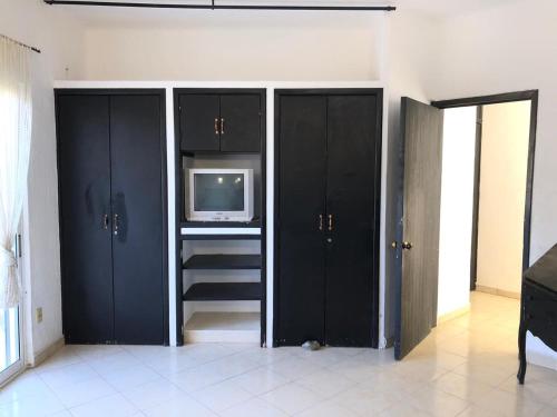 a living room with black cabinets and a tv at Casa y Villa Diamante, Manzanillo in Manzanillo