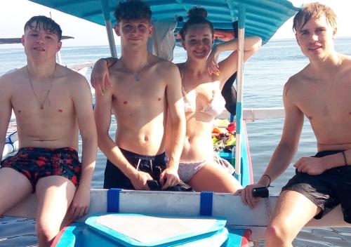 a group of young men sitting on the back of a boat at Apollo Hostel in Lovina