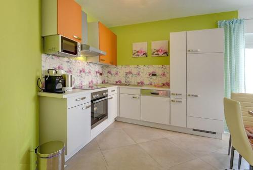 a kitchen with white cabinets and green and orange walls at Villa Marcelia in Pula