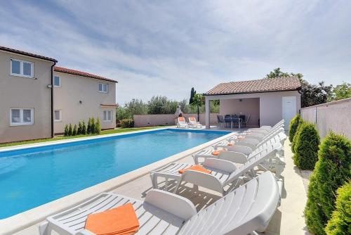 a swimming pool with chaise lounge chairs next to a house at Villa Marcelia in Pula