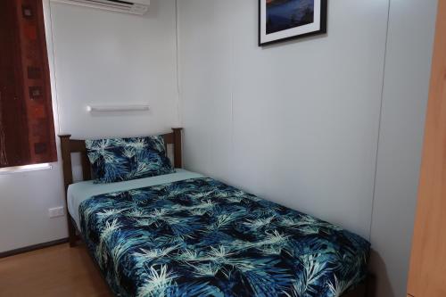 a small bedroom with a bed with a blue blanket at Mud Crab Motel in Derby