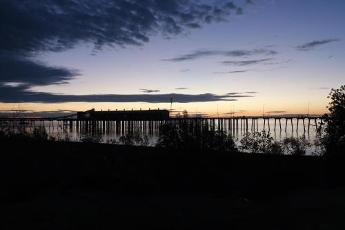 a sunset over a body of water with a pier at Mud Crab Motel in Derby