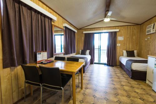 Habitación de hotel con mesa y 2 camas en Hotel Settlers, en Biloela