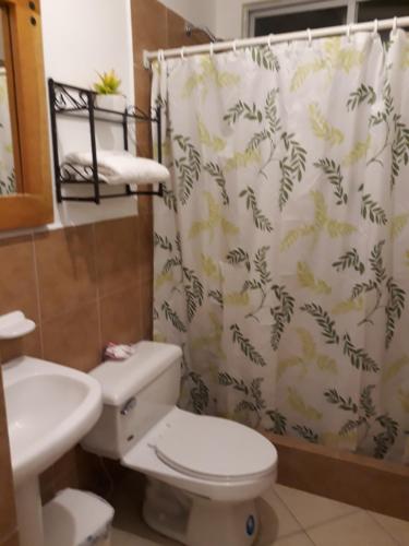 a bathroom with a toilet and a shower curtain at Arco Iris Atacames in Atacames