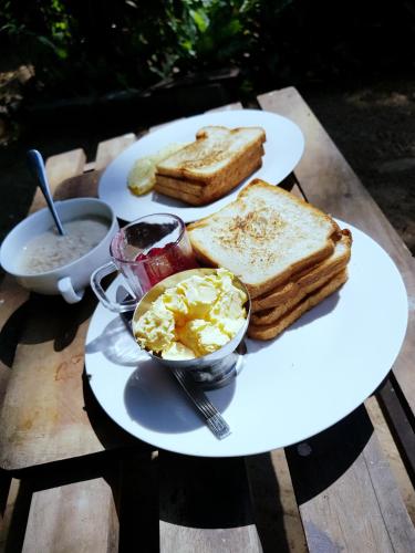 a plate of toast and eggs and bread on a table at Breeze Guest House in Trincomalee