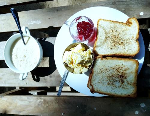a white plate with bread and butter and a drink at Breeze Guest House in Trincomalee