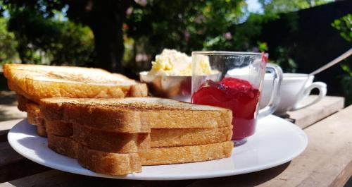 a plate with toast and a cup of jam and a bowl of fruit at Breeze Guest House in Trincomalee