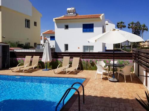 a pool with chairs and a table and an umbrella at Villa Charlotte in Protaras
