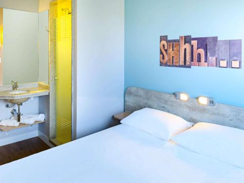 a bedroom with a bed and a sink and a mirror at ibis budget Sorocaba in Sorocaba