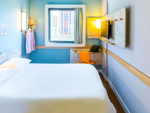 a small room with a bed and a window at ibis budget Sorocaba in Sorocaba