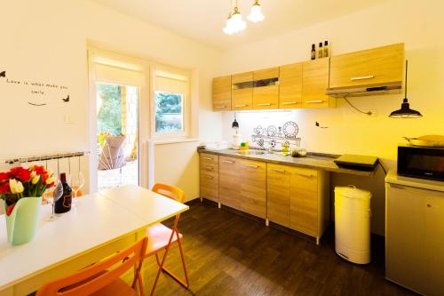a kitchen with wooden cabinets and a table and a dining room at Moments Apartment in Dekani