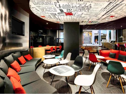 a restaurant with couches and tables and chairs at ibis Site du Futuroscope in Chasseneuil-du-Poitou