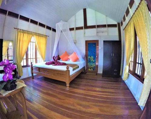 a bedroom with a bed with a mosquito net at Koh Jum Coral Bay Resort in Ko Jum